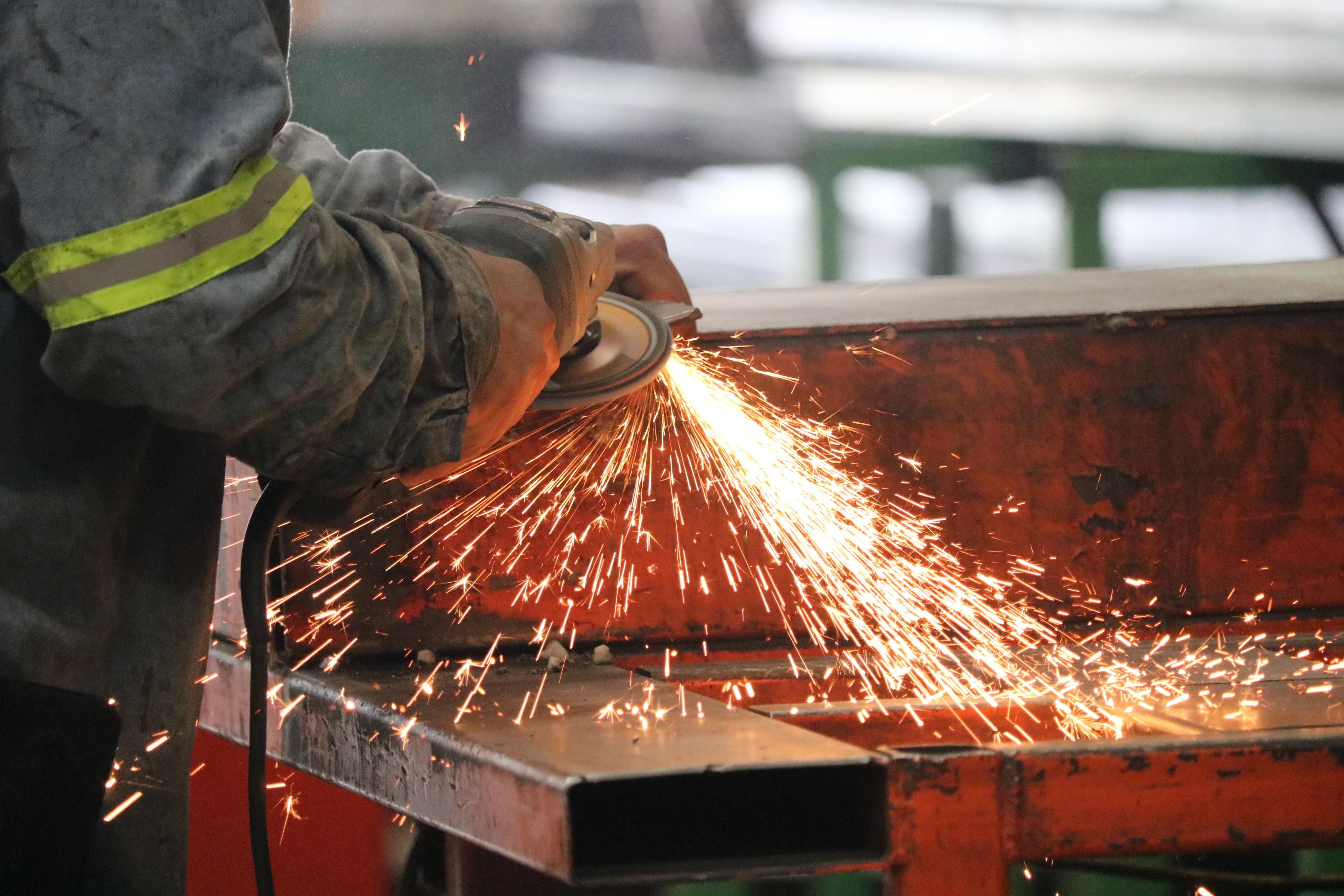 Trabajador esmerilando una estructura de acero entre chispas